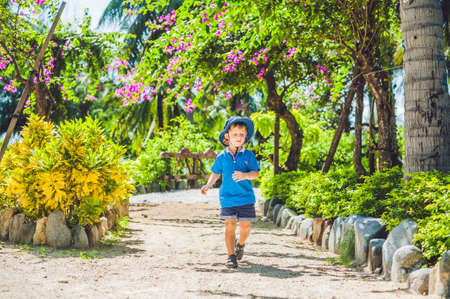 Boy runs through the tropical garden. Travelling with kids conceptの写真素材