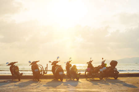 Silhouette scooter at seaside with sunset background.の写真素材