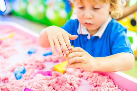 Boy playing with kinetic sand in preschool. The development of fine motor concept. Creativity Game concept.の写真素材