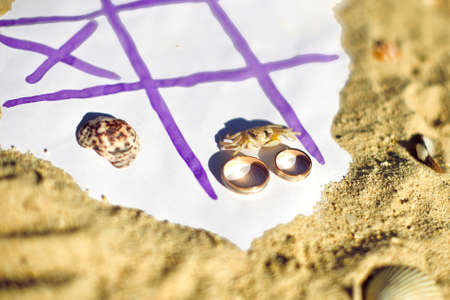 Tic Tac Toe and wedding rings on the beach. Wedding in the tropics concept.の写真素材