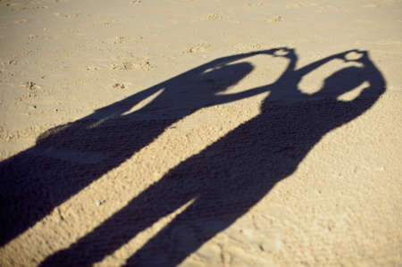 Silhouettes of couple or two lovers photography together, Shadow on the Ground, Woman gesture a heart-shaped arm, Concept of romantic. Vintage teenage style.の写真素材