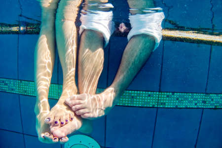 Legs of man and woman in the pool underwater.の写真素材