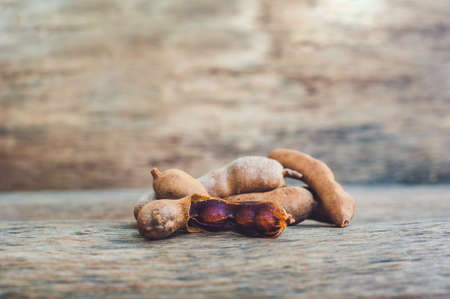 Sweet ripe tamarind pods on old wood background.の写真素材