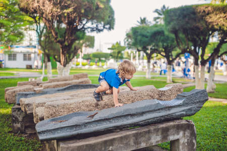 Cute blond boy climbs up the stone blocks on the playground. Childhood, concept.の写真素材