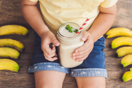 Boy holding a banana smoothie, proper nutrition conceptの写真素材