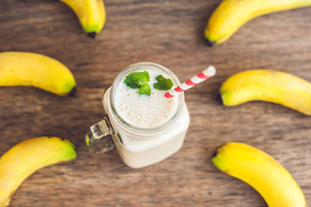 Banana cocktail and fresh bananas on the old wooden background, proper nutrition conceptの写真素材