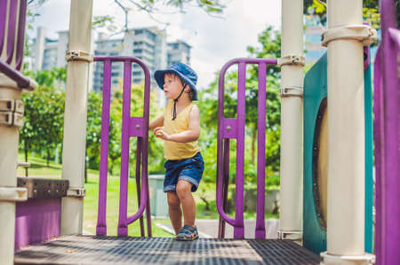Happy little kid boy playing at colorful playground. Adorable child having fun outdoors.