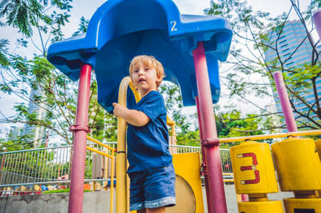 Happy little kid boy playing at colorful playground. Adorable child having fun outdoors.の写真素材