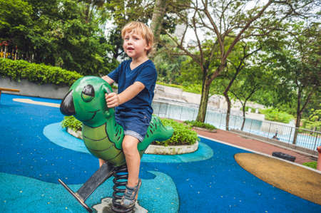 Happy little kid boy playing at colorful playground. Adorable child having fun outdoors.の写真素材