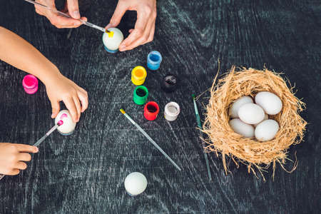 Happy easter A mother, father and their son painting Easter eggs. Happy family preparing for Easter.
