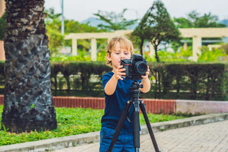 The Toddler boy takes pictures on a camera on a tripod.の写真素材