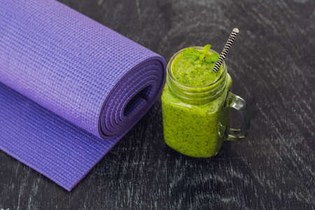 Green smoothies made of spinach and pineapple and a yoga mat. Healthy eating and sports concept.の写真素材