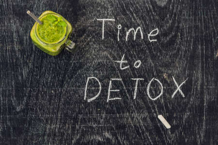 TIME TO DETOX chalk inscription on the wooden table and Green smoothies made of spinach.の写真素材
