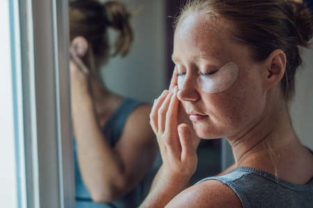 Portrait of Beauty Red-haired woman with eye patches showing an effect of perfect skinの写真素材