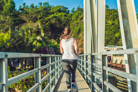 Beautiful woman running over bridge during sunset.の写真素材
