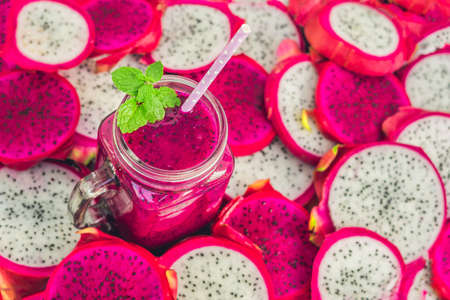 Smoothies of red organic dragon fruit and pieces of dragon fruit on an old wooden background.の写真素材