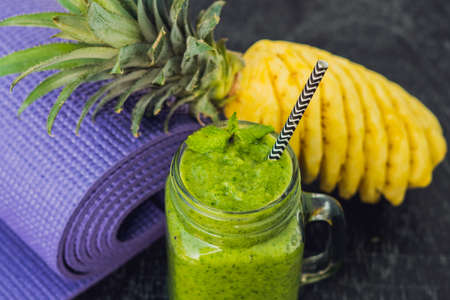 Green smoothies made of spinach and pineapple and a yoga mat. Healthy eating and sports concept.の写真素材
