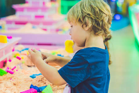 Boy playing with kinetic sand in preschool. The development of fine motor concept. Creativity Game concept.の写真素材