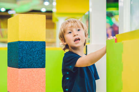 Happy boy playing indoors with big plastic construction blocks.の写真素材