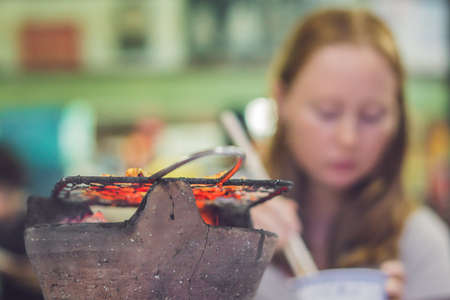 Girl frying meat on a small grill in a restaurant.の写真素材