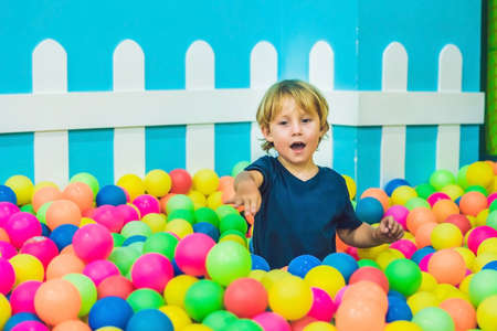 Happy little kid boy playing at colorful plastic balls playground high view. Funny child having fun indoors.の写真素材