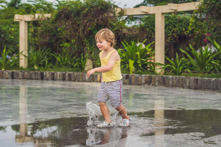 Little boy runs through a puddle. summer outdoor.の写真素材