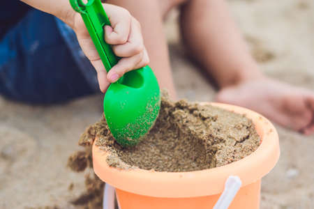Kid playing on the beach with the children's shovel and a bucket.の写真素材