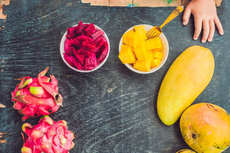 Little cute boy eating mango on the terrace.の写真素材
