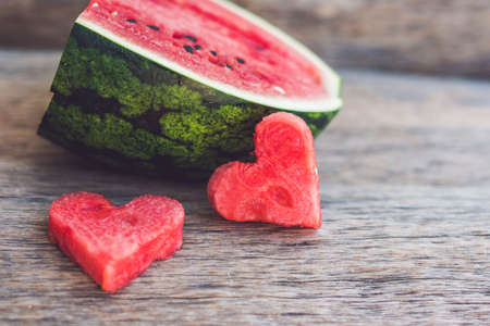 Healthy watermelon smoothie with mint, a piece of watermelon, hearts and a striped straw on a wood background.の写真素材