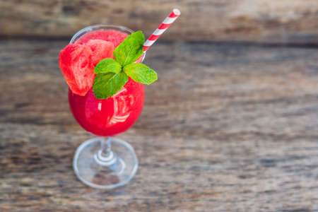 Healthy watermelon smoothie with mint and striped straws on a wood background.の写真素材