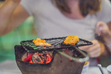 Girl frying meat on a small grill in a restaurant.の写真素材