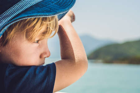 Adorable boy looking to the blue sea from yacht board in sunny day.の写真素材