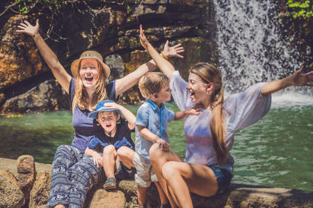 Tourists women and children against the waterfall with their hands raised.の写真素材
