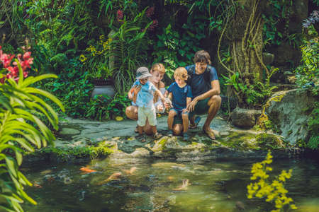 happy family feeding colorful Catfish in tropical pond.の写真素材
