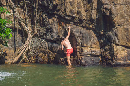 A man climbs up a mountain from the water.の写真素材