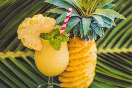 Pineapple and pineapple smoothies against the background of a branch of a palm tree.の写真素材