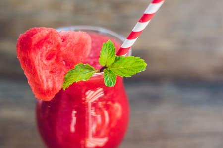 Healthy watermelon smoothie with mint and striped straws on a wood background.の写真素材