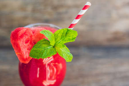 Healthy watermelon smoothie with mint and striped straws on a wood background.の写真素材