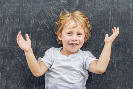 Top view of a little blond kid boy with space for text and symbols on the old wooden background. Concept for confusion, brainstorming and choice. copy spaceの写真素材