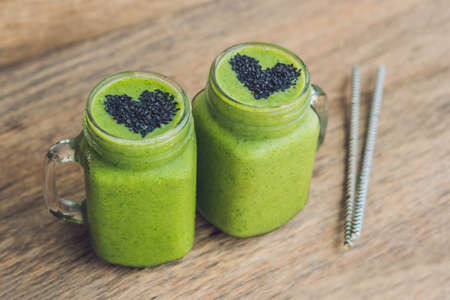 Fresh green smoothie with banana and spinach with heart of sesame seeds. Love for a healthy raw food concept.の写真素材