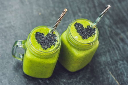 Fresh green smoothie with banana and spinach with heart of sesame seeds. Love for a healthy raw food concept.の写真素材