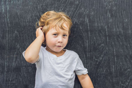 Top view of a little blond kid boy with space for text and symbols on the old wooden background. Concept for confusion, brainstorming and choice. copy spaceの写真素材