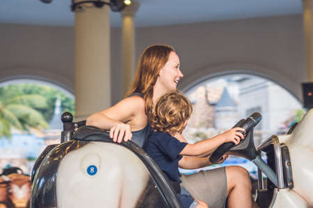 Mom and son having a ride in the bumper car at the amusement park.