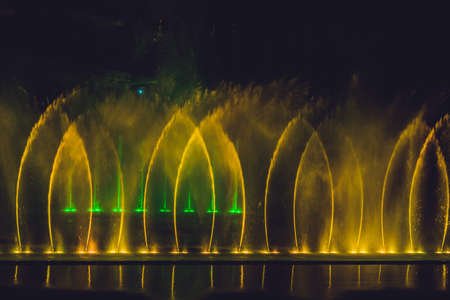 Multicolored dancing water jet fountain in the dark.の写真素材