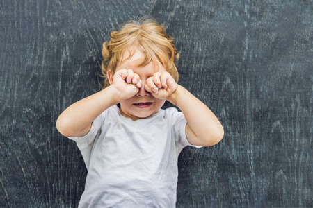 Top view of a little blond kid boy with space for text and symbols on the old wooden background....