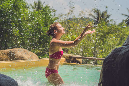 Young woman relaxing under a waterfall in aquapark. Vacation conceptの写真素材