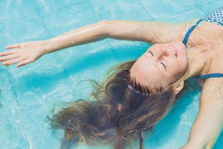 Beautiful young woman floating in pool relaxing Top view. Holiday concept.の写真素材