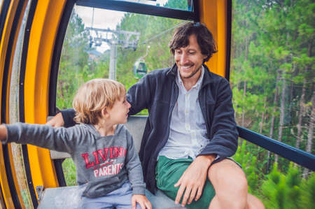 Father and son in ski lift cabin in summer. Passengers on a cable car.の写真素材