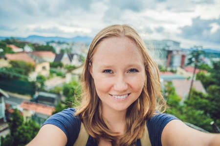Young woman doing selfie on the background of the city of Dalat, Vietnam.の写真素材