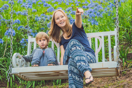happy mother pushing laughing son on swing in a park.の写真素材